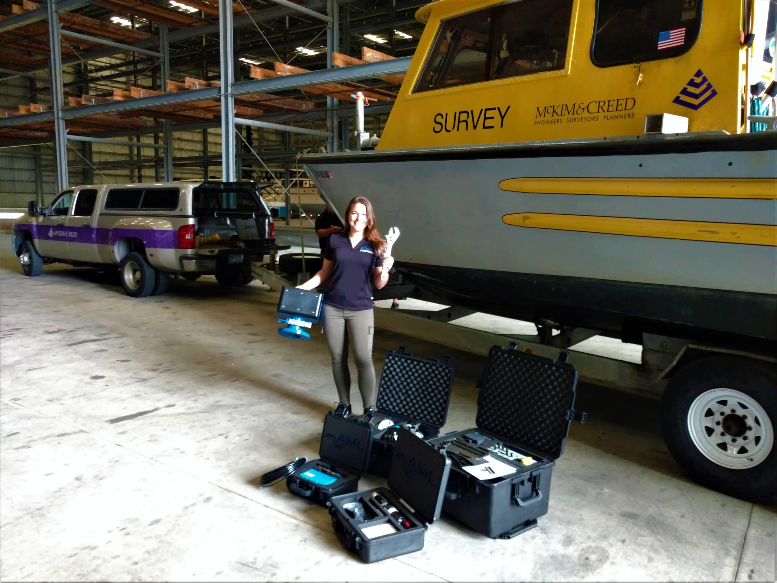female surveyor standing next to MBES equipment and boat on a tow trailer